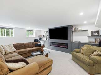 Experience ultimate relaxation in this modern basement living room, featuring a plush sectional sofa and a cozy armchair perfect for unwinding.