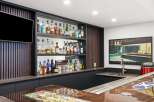 Elevate your entertaining with this stunning home bar, featuring a sleek modern design with ample shelving for a vast liquor collection.