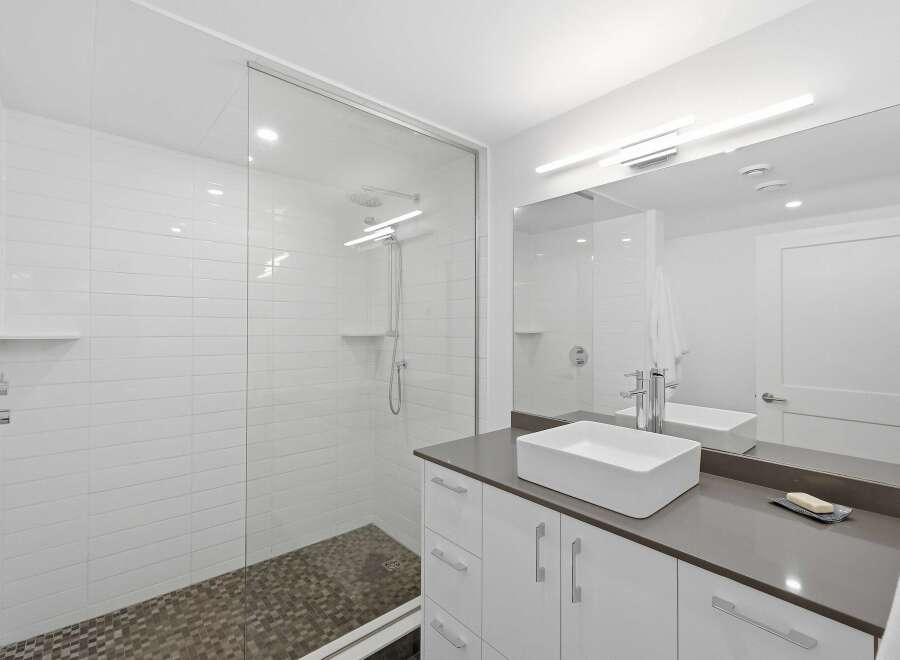 Experience modern luxury in this stunning bathroom featuring a spacious glass-enclosed shower with sleek tilework and a rainfall showerhead.