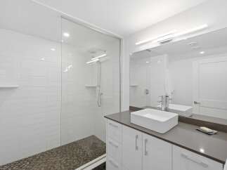 Experience modern luxury in this stunning bathroom featuring a spacious glass-enclosed shower with sleek tilework and a rainfall showerhead.