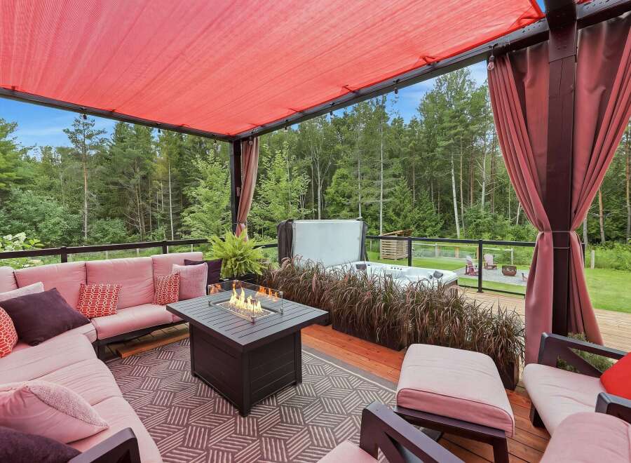 Experience ultimate relaxation on this stunning covered patio, featuring a plush sectional sofa, a modern fire pit, and a luxurious hot tub.