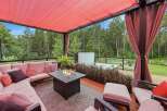 Experience ultimate relaxation on this stunning covered patio, featuring a plush sectional sofa, a modern fire pit, and a luxurious hot tub.