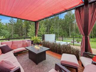 Experience ultimate relaxation on this stunning covered patio, featuring a plush sectional sofa, a modern fire pit, and a luxurious hot tub.