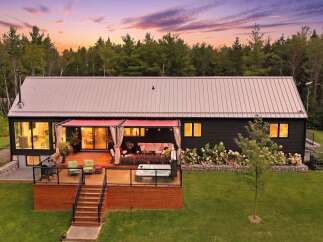 Experience modern living in this stunning home featuring a spacious wooden deck with a relaxing hot tub and comfortable outdoor seating.