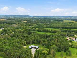 Discover this stunning property featuring a modern dark-colored home nestled amidst lush greenery and mature trees.