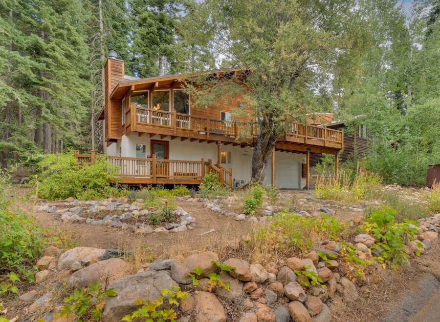 Nestled amidst towering trees, this charming mountain home offers a serene retreat with its multi-level decks and natural wood exterior.
