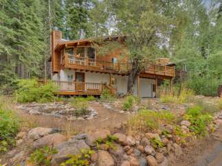 Nestled amidst towering trees, this charming mountain home offers a serene retreat with its multi-level decks and natural wood exterior.