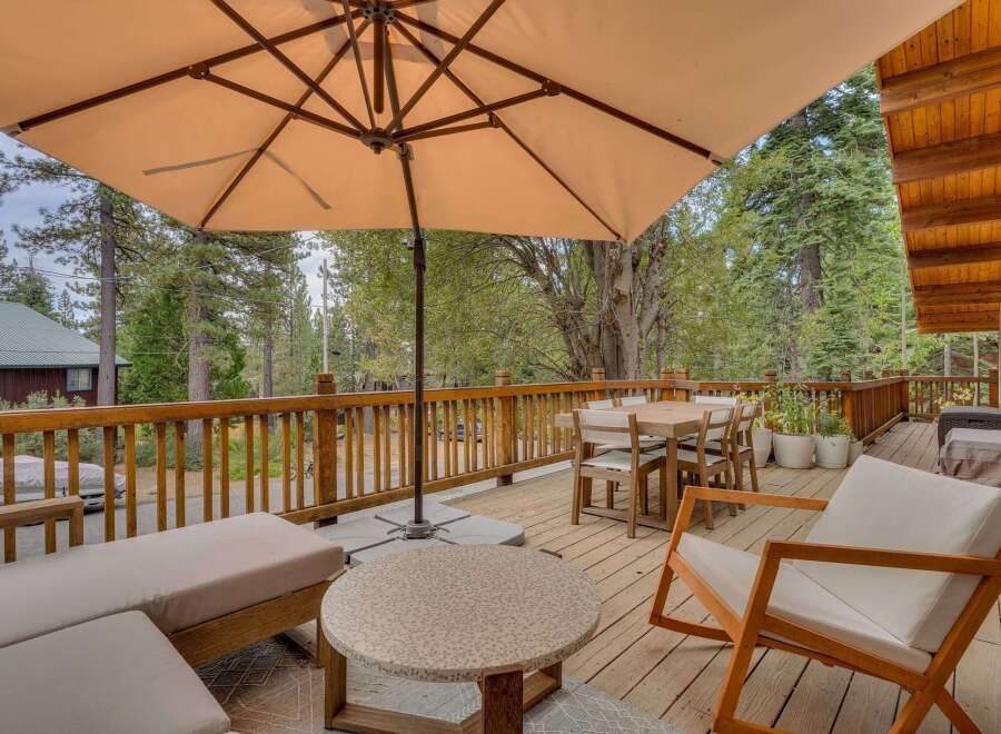 Enjoy outdoor living on this spacious wooden deck, perfect for entertaining or relaxing amidst a serene forest setting.