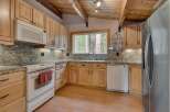 This charming kitchen features light wood cabinetry and granite countertops, offering a warm and inviting atmosphere.