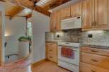 Discover a charming kitchen featuring light wood cabinetry and a built-in microwave, complemented by granite countertops and a tiled backsplash.