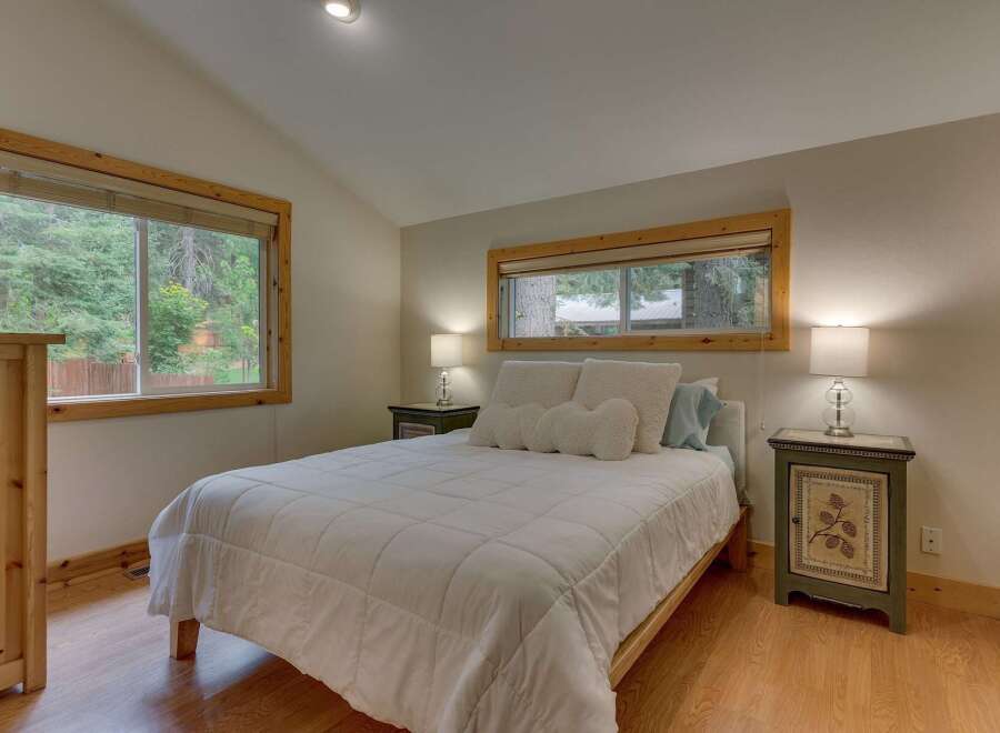 This charming bedroom features a comfortable queen-size bed adorned with plush white bedding and decorative pillows.