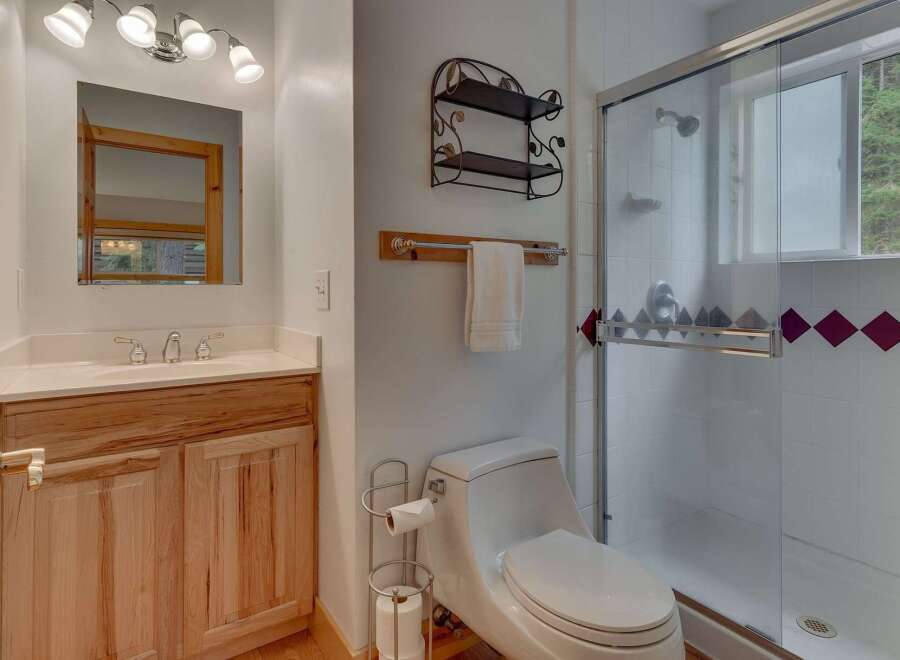 This charming bathroom features a light wood vanity with a white countertop and a modern sink.