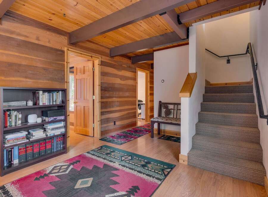 Step into this charming cabin-style entryway featuring warm wood paneling and exposed beams.