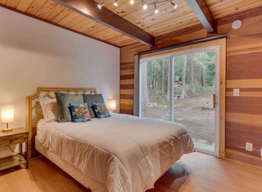 Experience cozy cabin living in this charming bedroom featuring a comfortable queen-size bed adorned with decorative pillows.
