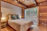 Experience cozy cabin living in this charming bedroom featuring a comfortable queen-size bed adorned with decorative pillows.