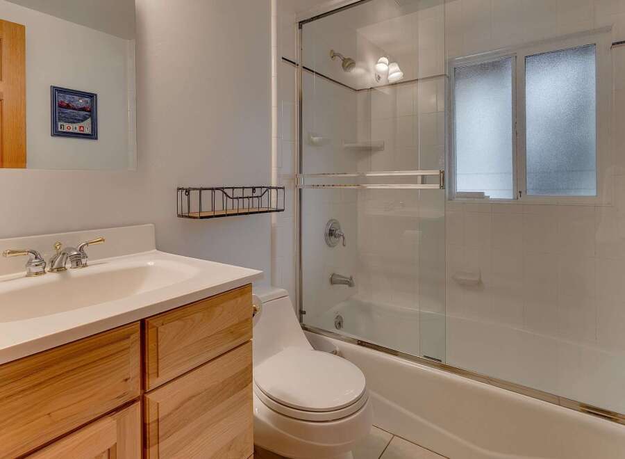 This bathroom features a modern vanity with ample storage and a sleek sink, complemented by a spacious bathtub and shower combination.