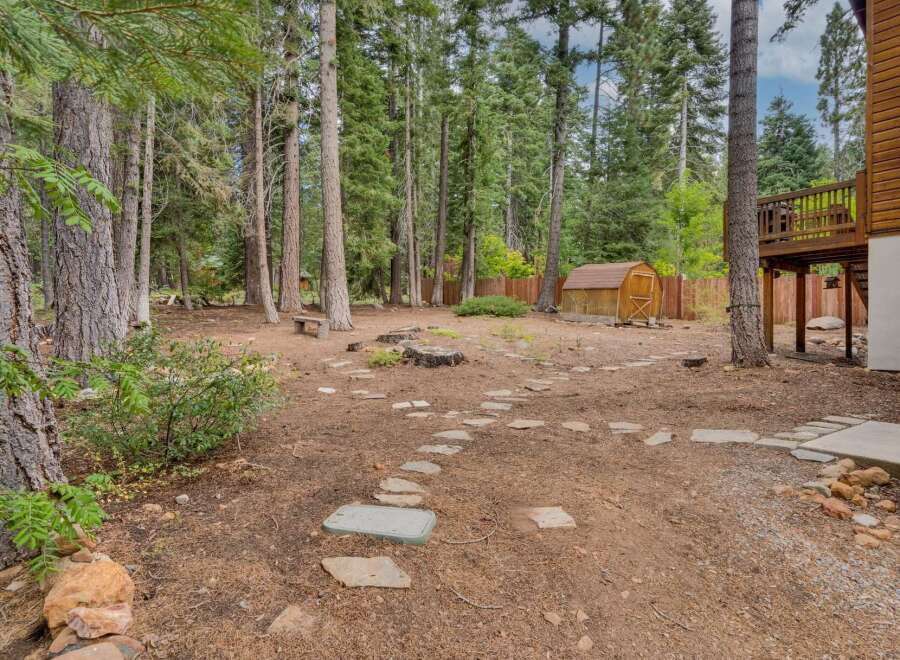 Discover your private oasis with this charming backyard, featuring a rustic stone pathway leading to a quaint wooden shed.