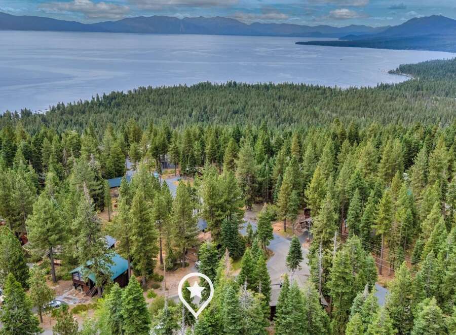 Nestled amidst a dense forest of pine trees, this property offers a serene retreat with stunning views of a vast lake and distant mountains.