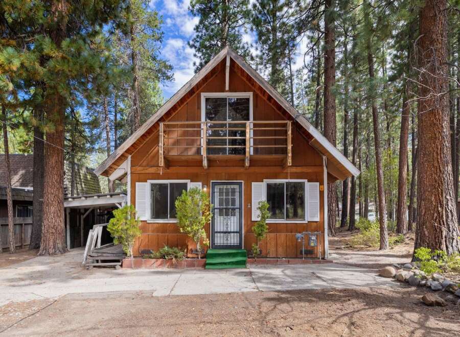 Charming A-frame cabin nestled amongst tall pine trees, offering a rustic retreat.