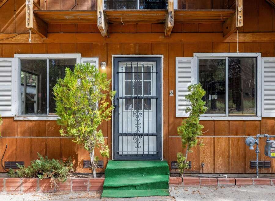 Charming wooden cabin exterior featuring a welcoming entrance with a security door and vibrant green steps.
