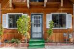 Charming wooden cabin exterior featuring a welcoming entrance with a security door and vibrant green steps.