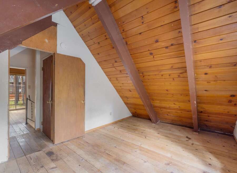 Discover the unique charm of this attic space, featuring a sloped wooden ceiling and exposed beams that add rustic character.