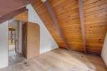 Discover the unique charm of this attic space, featuring a sloped wooden ceiling and exposed beams that add rustic character.