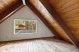 Discover the potential of this charming attic space, featuring exposed wooden beams and a large window offering scenic views.