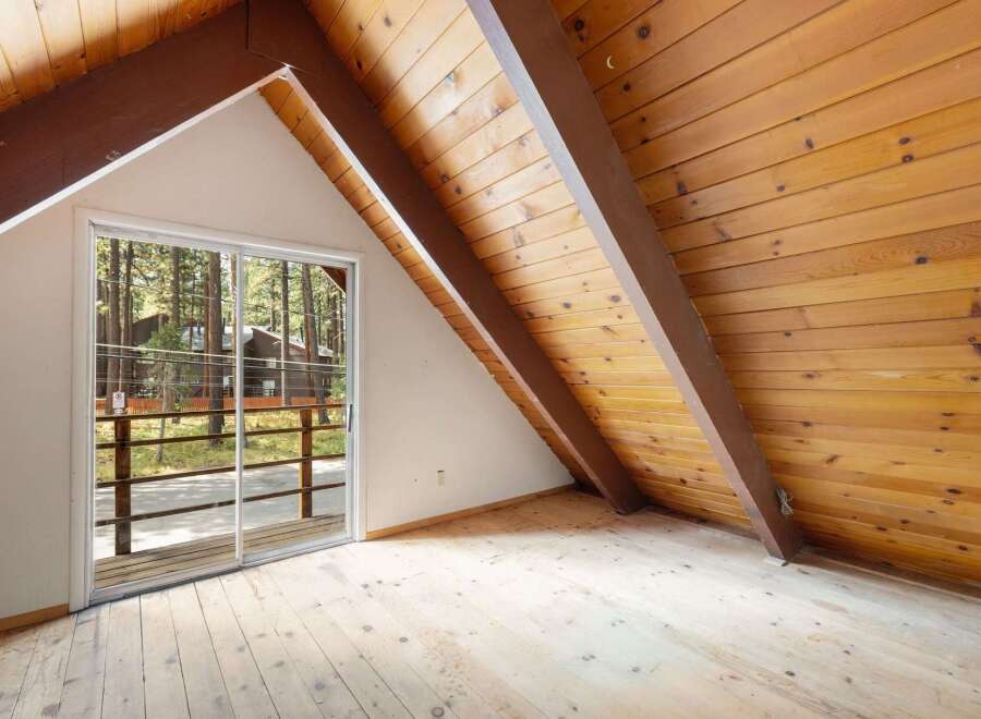 Experience rustic charm in this attic room featuring a vaulted wood-paneled ceiling and exposed beams.