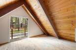 Experience rustic charm in this attic room featuring a vaulted wood-paneled ceiling and exposed beams.