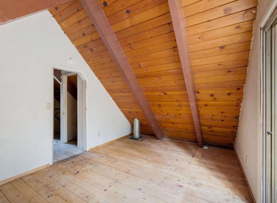 Discover the unique charm of this attic space, featuring a warm wooden plank ceiling and exposed beams that add rustic character.