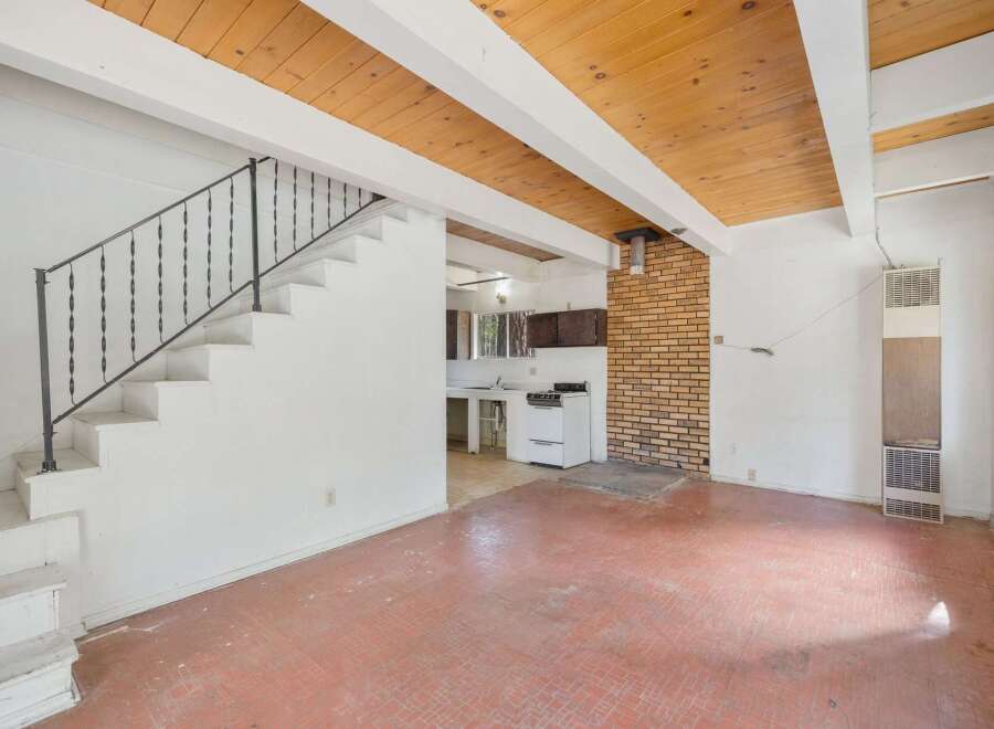 This charming home features a unique open-concept living space with a rustic wood-paneled ceiling and exposed beams, creating a warm and inviting atmosphere.