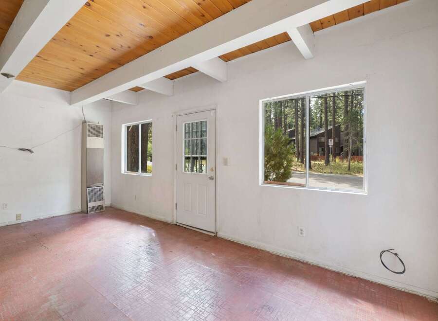 Discover a cozy interior with a charming wood-paneled ceiling and exposed beams, creating a warm and inviting atmosphere.