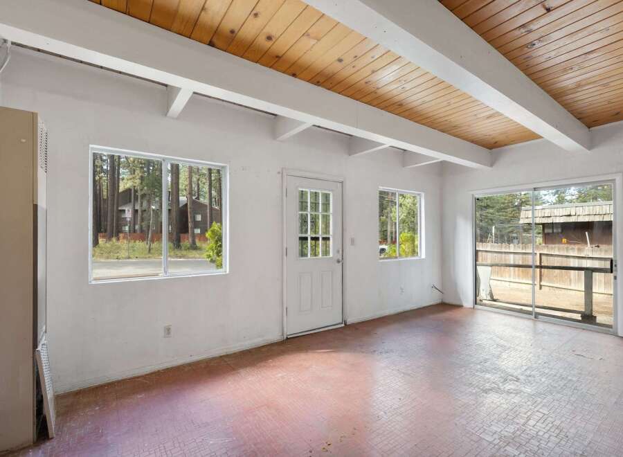 Discover the potential in this versatile space, featuring a bright interior with a wood-paneled beamed ceiling and ample natural light from multiple windows.