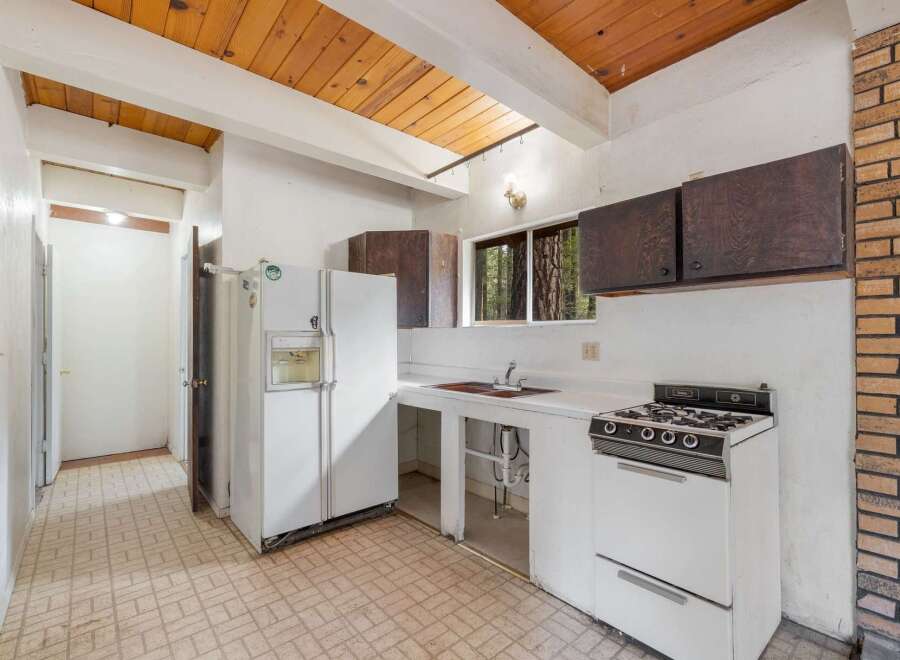 This charming kitchen features a rustic wooden beamed ceiling and a brick accent wall, adding warmth and character.