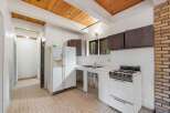 This charming kitchen features a rustic wooden beamed ceiling and a brick accent wall, adding warmth and character.