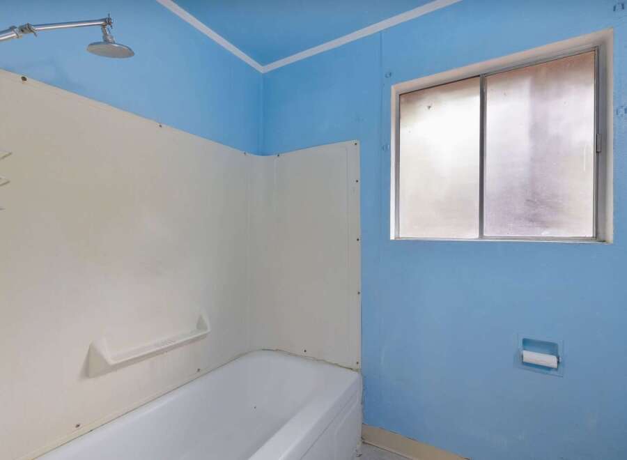 This bathroom features a classic white bathtub with a built-in shelf and a shower head.