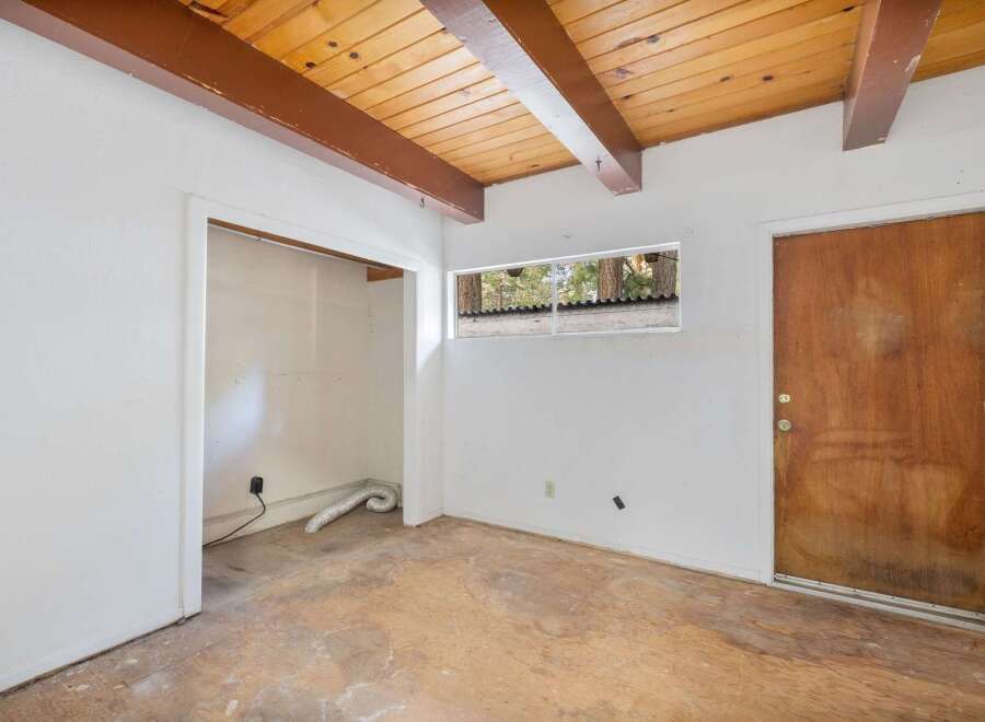Discover the potential in this fixer-upper, featuring a rustic wood-beamed ceiling and a charming wooden door.