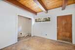 Discover the potential in this fixer-upper, featuring a rustic wood-beamed ceiling and a charming wooden door.