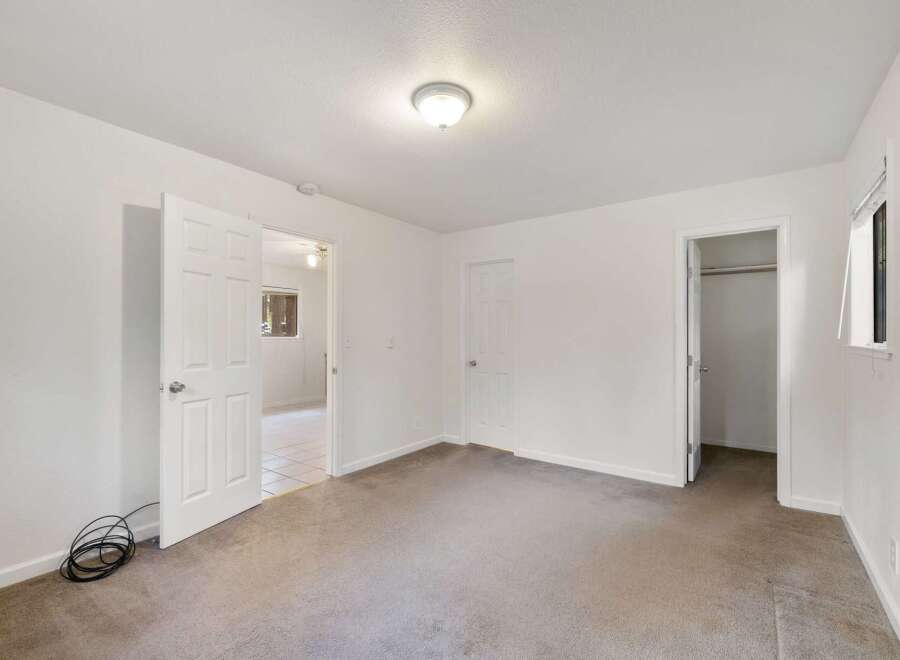 This spacious bedroom features neutral carpeting and ample natural light, creating a serene atmosphere.