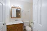 This bathroom features a spacious vanity with ample storage, a bright mirror with overhead lighting, and a clean white toilet.