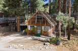 Nestled amongst tall pine trees, this charming cabin offers a rustic retreat with its warm wood exterior and inviting porch.