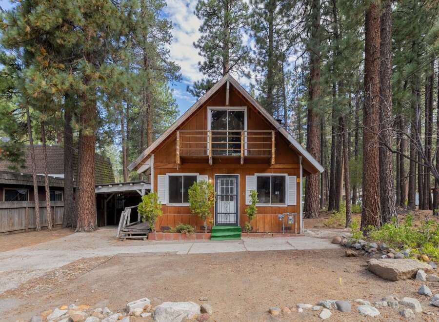 Charming A-frame cabin nestled among tall pine trees, offering a serene mountain retreat.