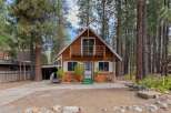 Charming A-frame cabin nestled among tall pine trees, offering a serene mountain retreat.