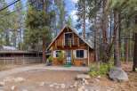 Charming A-frame cabin nestled amongst tall pine trees, offering a serene mountain retreat.