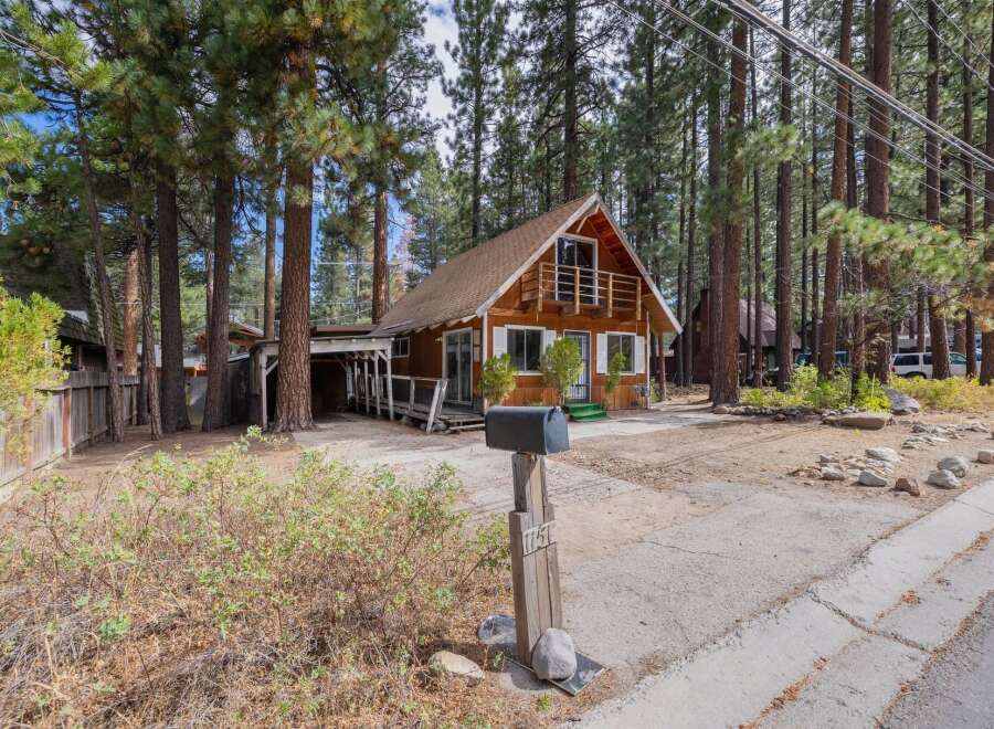 Charming A-frame cabin nestled among tall pine trees, offering a rustic mountain retreat.