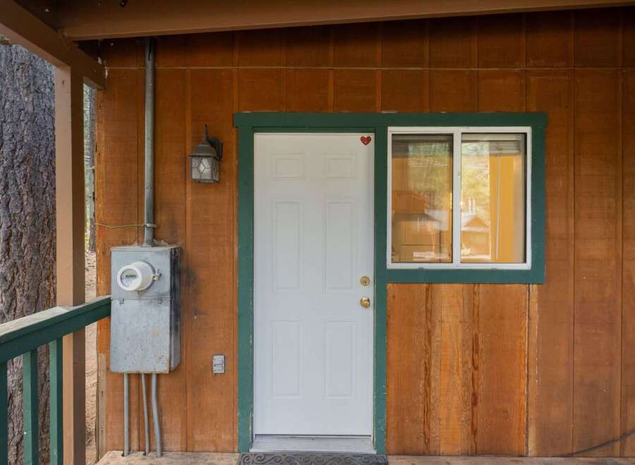 Discover this charming property featuring a welcoming white front door with a decorative red heart accent, complemented by a classic outdoor lantern.