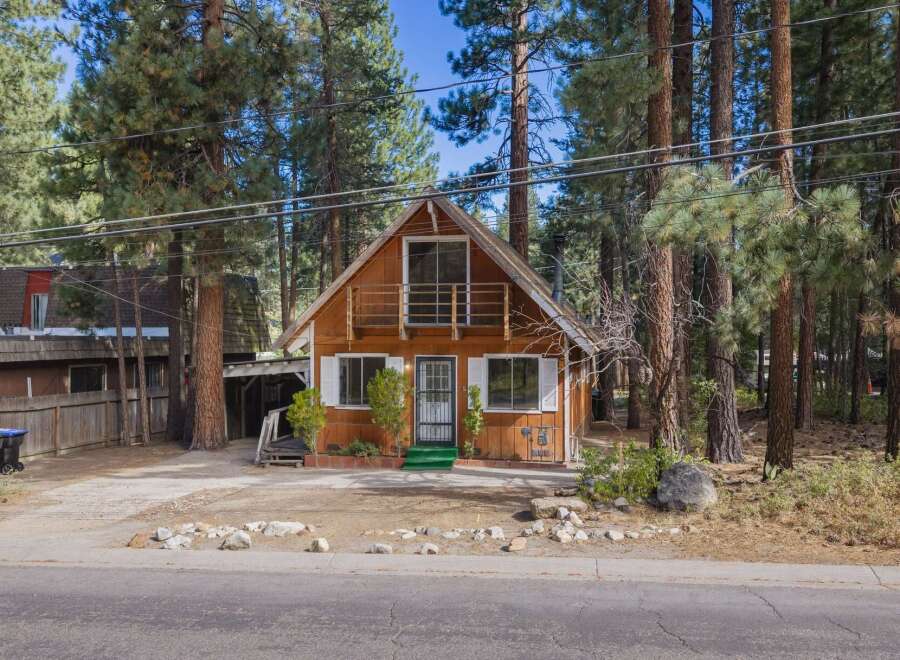 Charming A-frame cabin nestled amongst tall pine trees, offering a rustic mountain retreat.