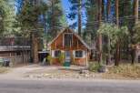 Charming A-frame cabin nestled amongst tall pine trees, offering a rustic mountain retreat.