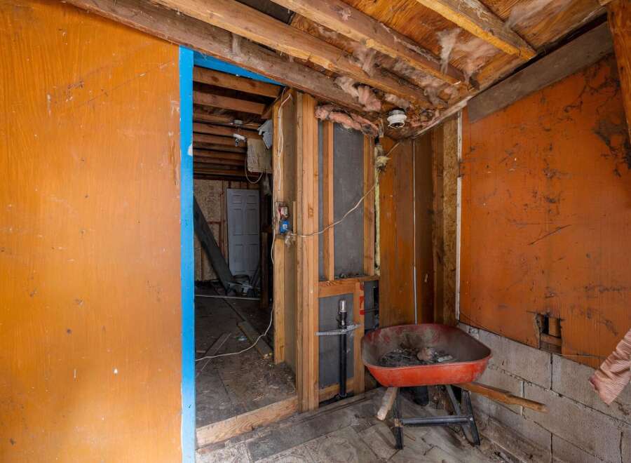 This image showcases a room undergoing renovation, highlighting exposed wooden beams, insulation, and unfinished walls, suggesting a potential fixer-upper opportunity.